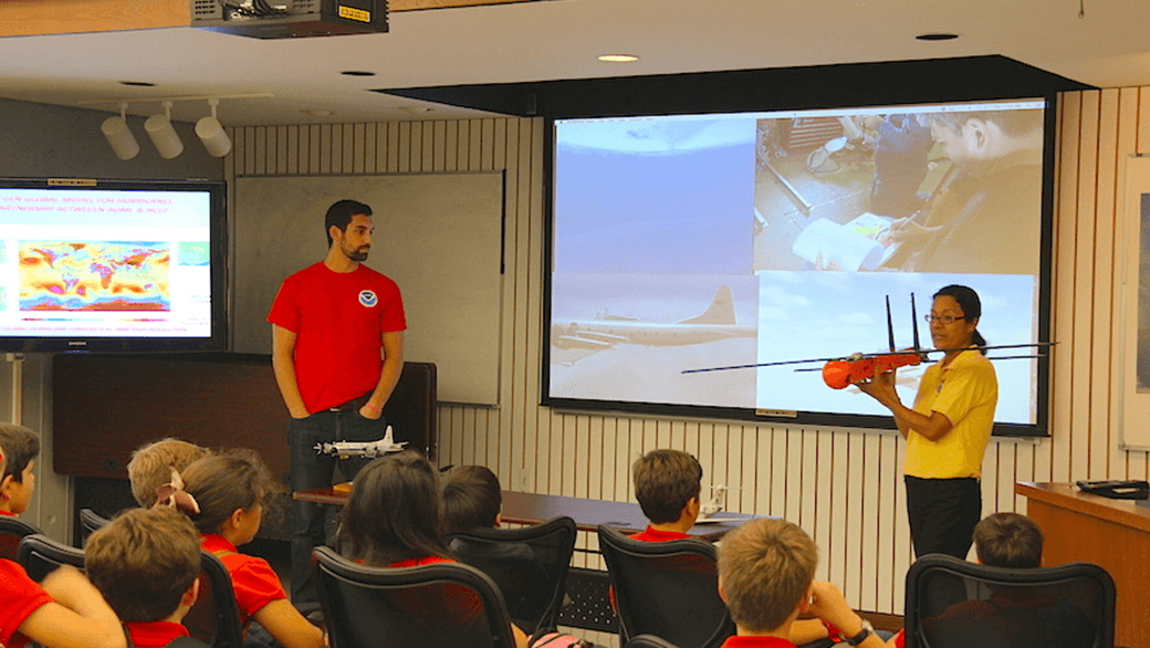 Gus Alaka y Shirley Murillo explican a los escolares los drones para huracanes. Crédito de la foto: NOAA.
