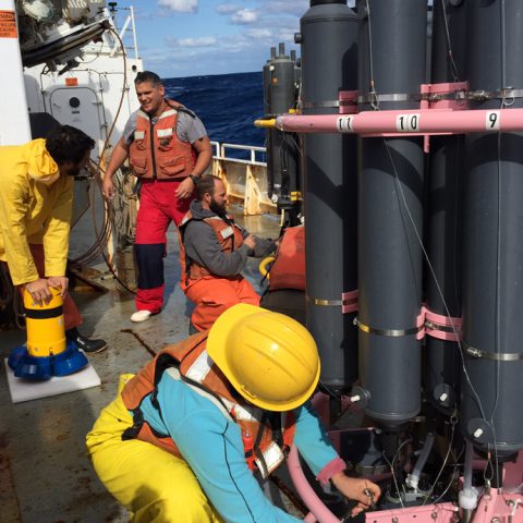 Scientist taking a water sample from a CTD rosette. Photo Credit: NOAA.