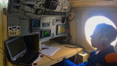A hurricane researcher monitors storm conditions at a work station aboard the P-3 aircraft. Image credit: NOAA