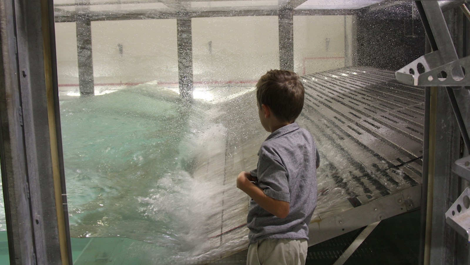 El niño observa el tanque de olas en acción durante el día de llevar a su hijo al trabajo. Crédito de la foto: NOAA AOML.