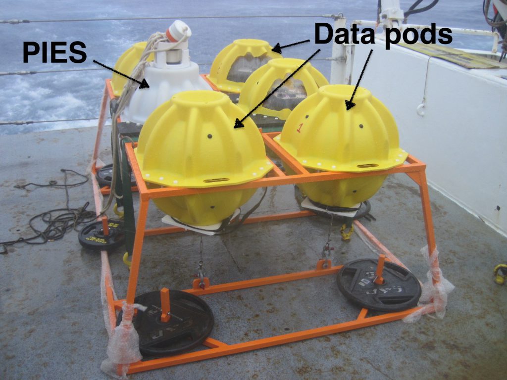 Photograph of a Pressure-equipped Inverted Echo Sounder (PIES) package additionally equipped with the AOML prototype ABIISS data pod retrieval system. The white sphere is a standard PIES instrument, while the yellow spheres are data pods. Photo Credit: NOAA