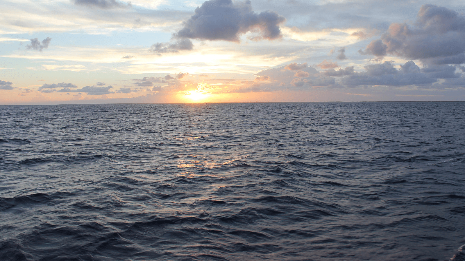 A sunset above on the horizon of a dark blue ocean