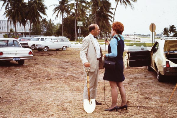 Colored image from AOML's Archive of AOML's first director Dr. Harris B. Stewart Jr. holding a golden ground-breaking shovel while speaking with a TV reporter.