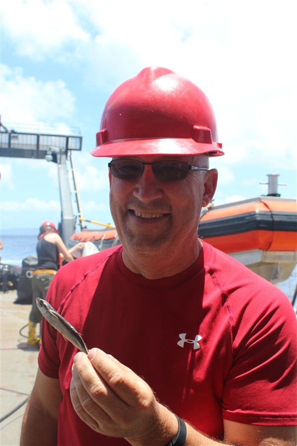 John Lamkin holds up a flying fish that found its way aboard. Image credit: NOAA