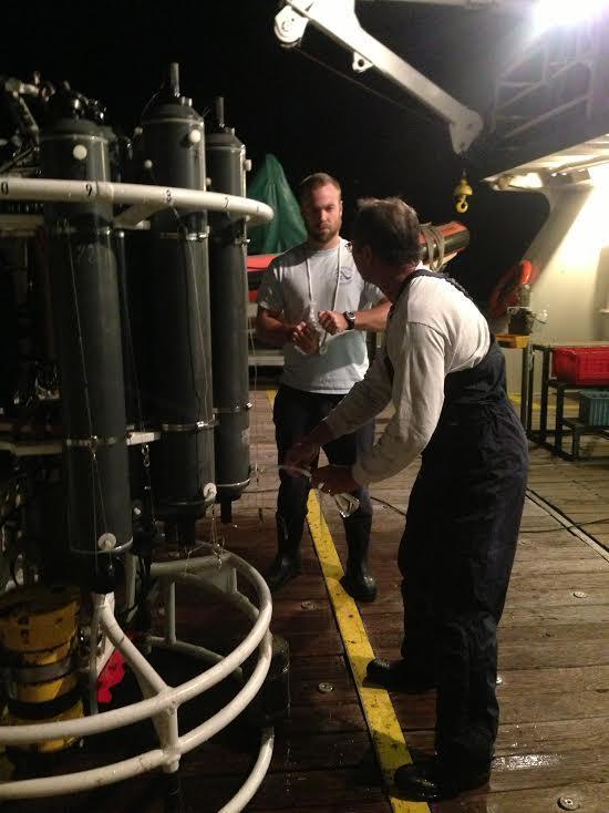Jay Hooper and Robert Roddy draw samples from large niskin bottles fixed to the CTD/O2/LADCP instrument package for dissolved oxygen and salinity sensor calibration following a station. Image credit: NOAA.