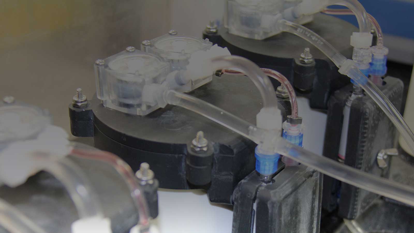 Image of an Environmental DNA sampler being tested in the lab. A closeup of the tops of the devices shows water moving through tubes as it is being test-sampled in the lab. Photo Credit, NOAA.