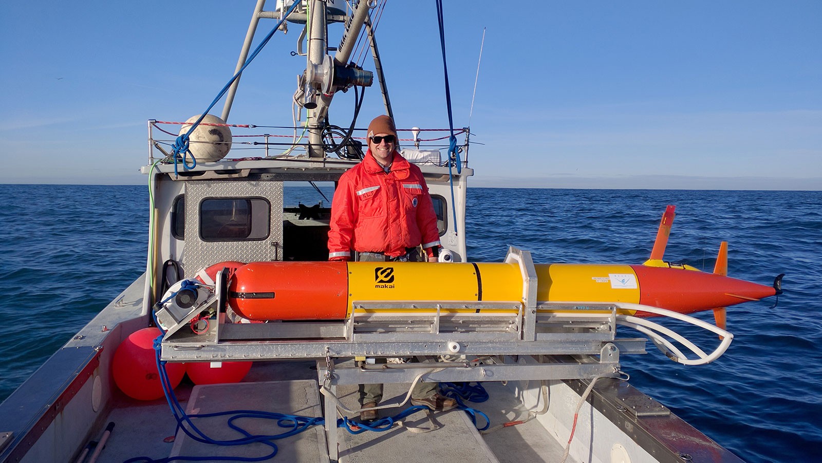 A NOAA Scientist stands next to an eAUV