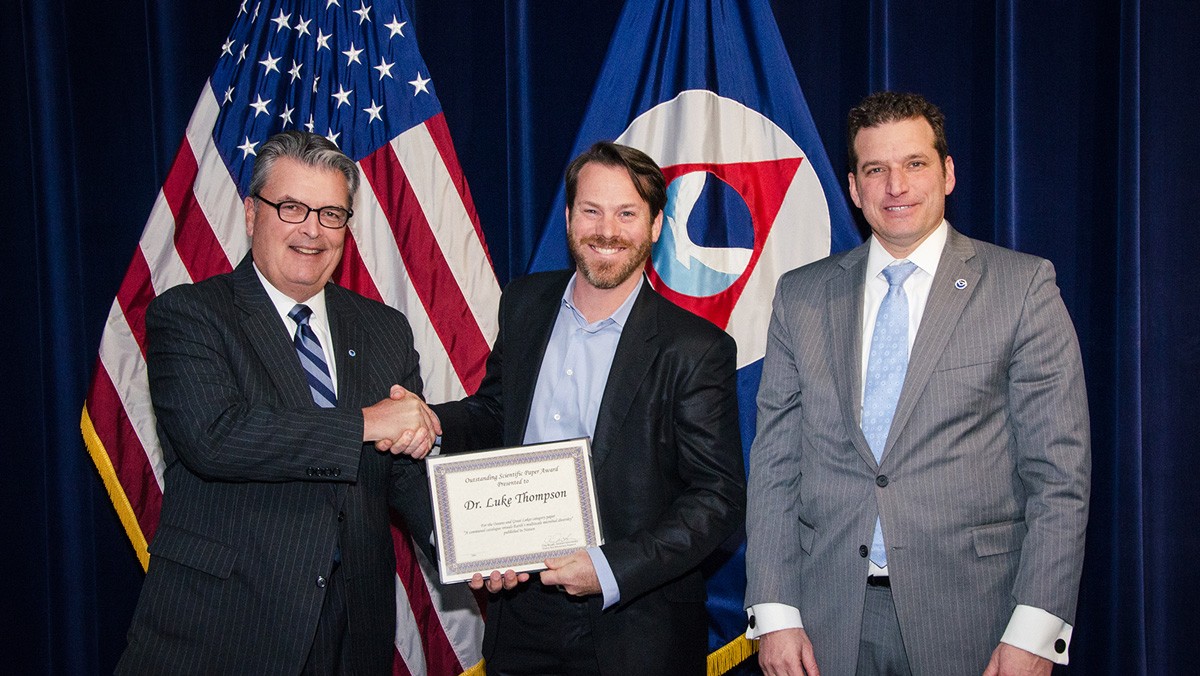 El Dr. Luke Thompson (centro) es felicitado por el Administrador Auxiliar de la OAR Craig McLean (izquierda) y Stuart Levenbach de la Oficina del Subsecretario/Administrador de la NOAA (derecha) en la Ceremonia de Premios de la OAR en Silver Spring, Maryland el 12 de marzo.