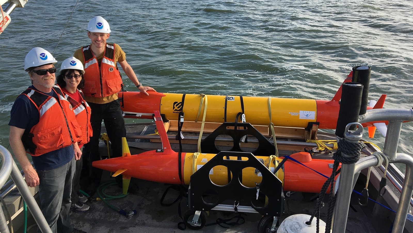 NOAA scientists stand next to an eAUV equipped with a 3rd Generation Environmental Sample Processor before deployment.