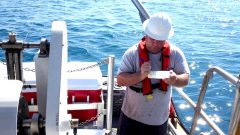 Charles Featherstone notating a sample bottle from a cast of the CTD instrument package off of Broward County. Image credit: NOAA