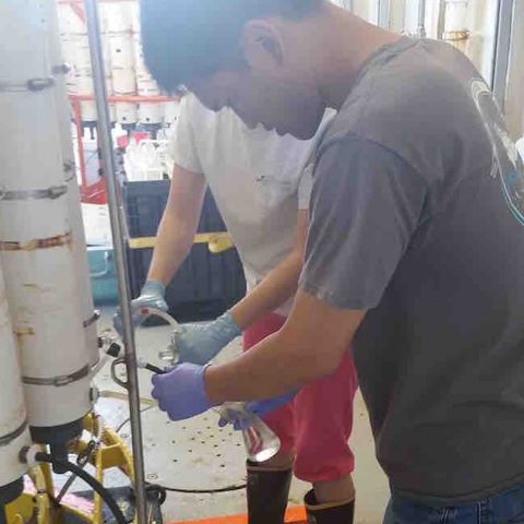 A researcher takes a sample from a Niskin bottle found on the CTD. Image credit: NOAA