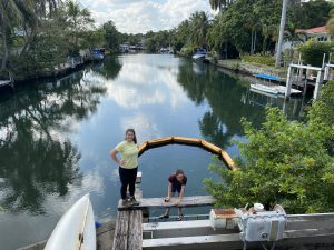 a photo of two collaborating scientists as they deploy water sampling technology into the waterway