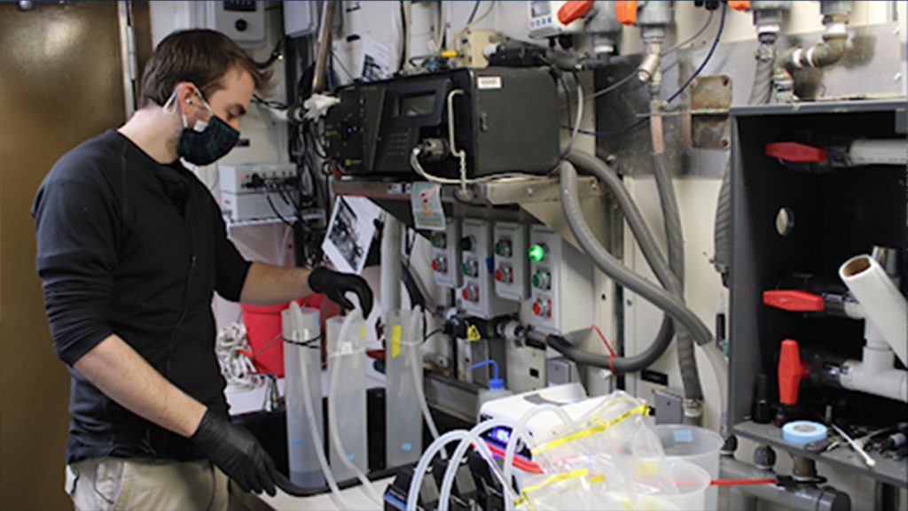 Sean Anderson se muestra filtrando agua de mar para la recogida de ADN ambiental (eDNA)