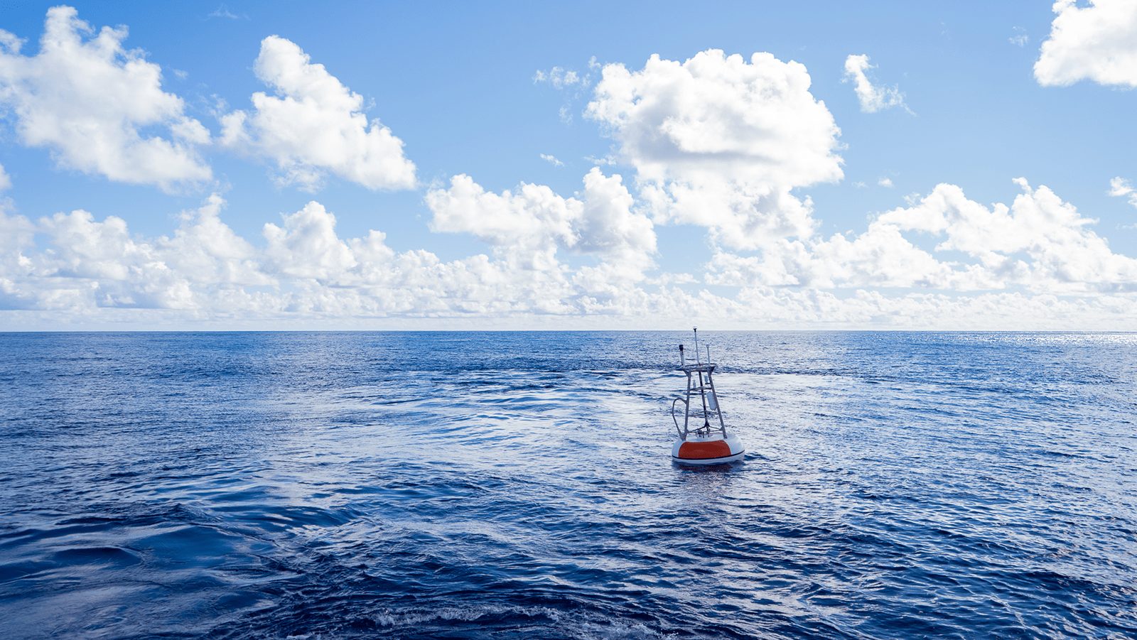 A large red and white buoy floats in the open ocean.