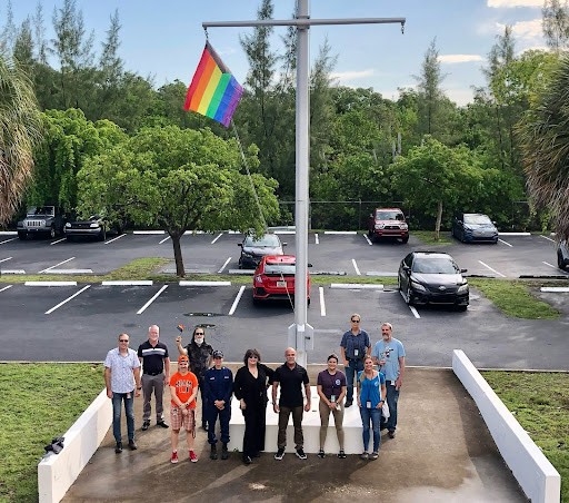 Eleven AOML employees stand in front of the Pride flag outside of AOML.