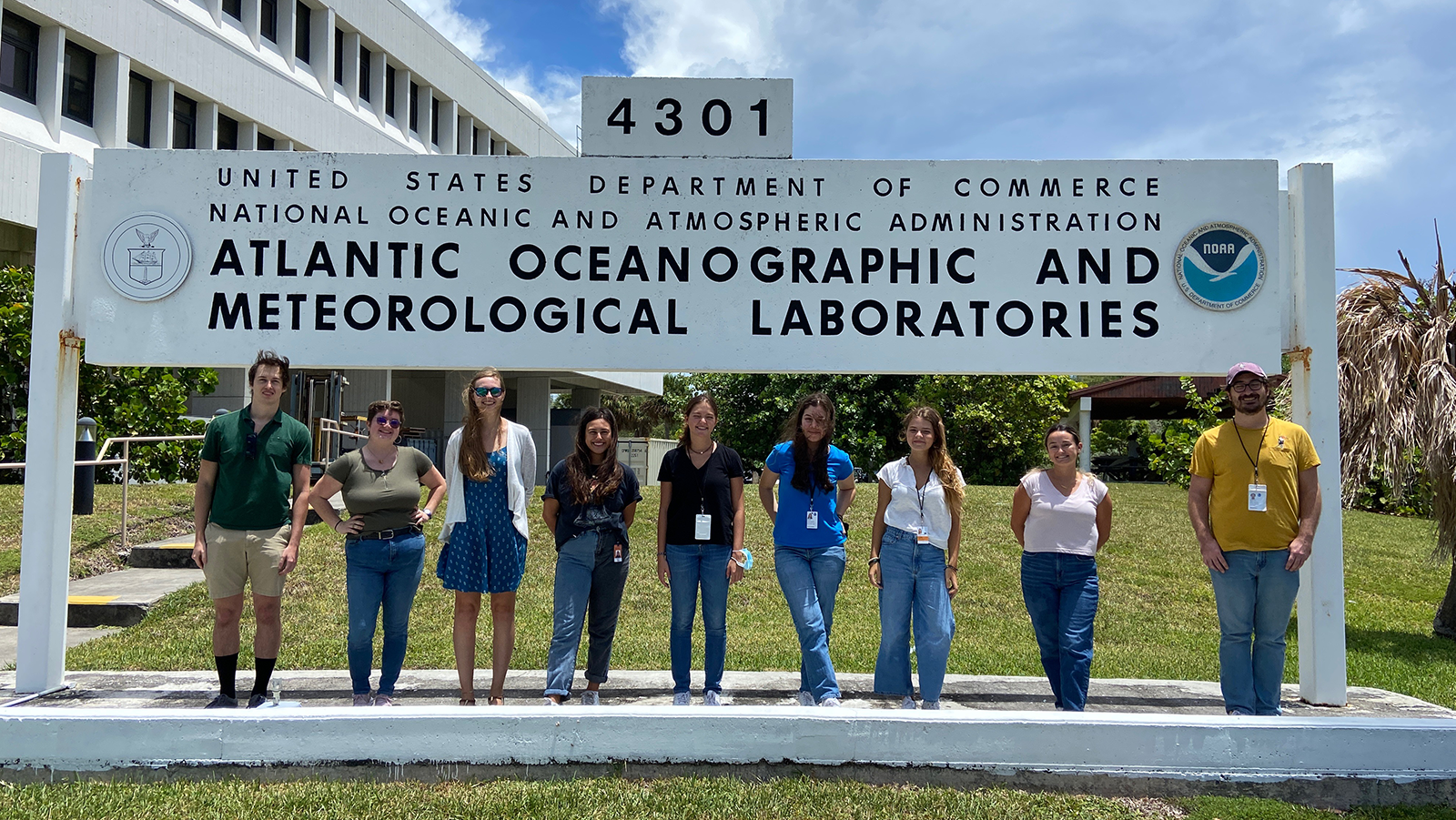 Nine AOML Summer 2022 interns stand in front of the AOML sign.