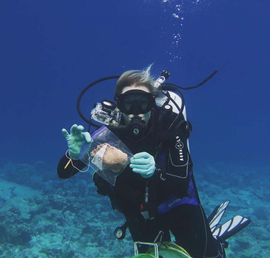 Jennifer McWhorter holding a zip top baggie with a coral in it while scuba diving.