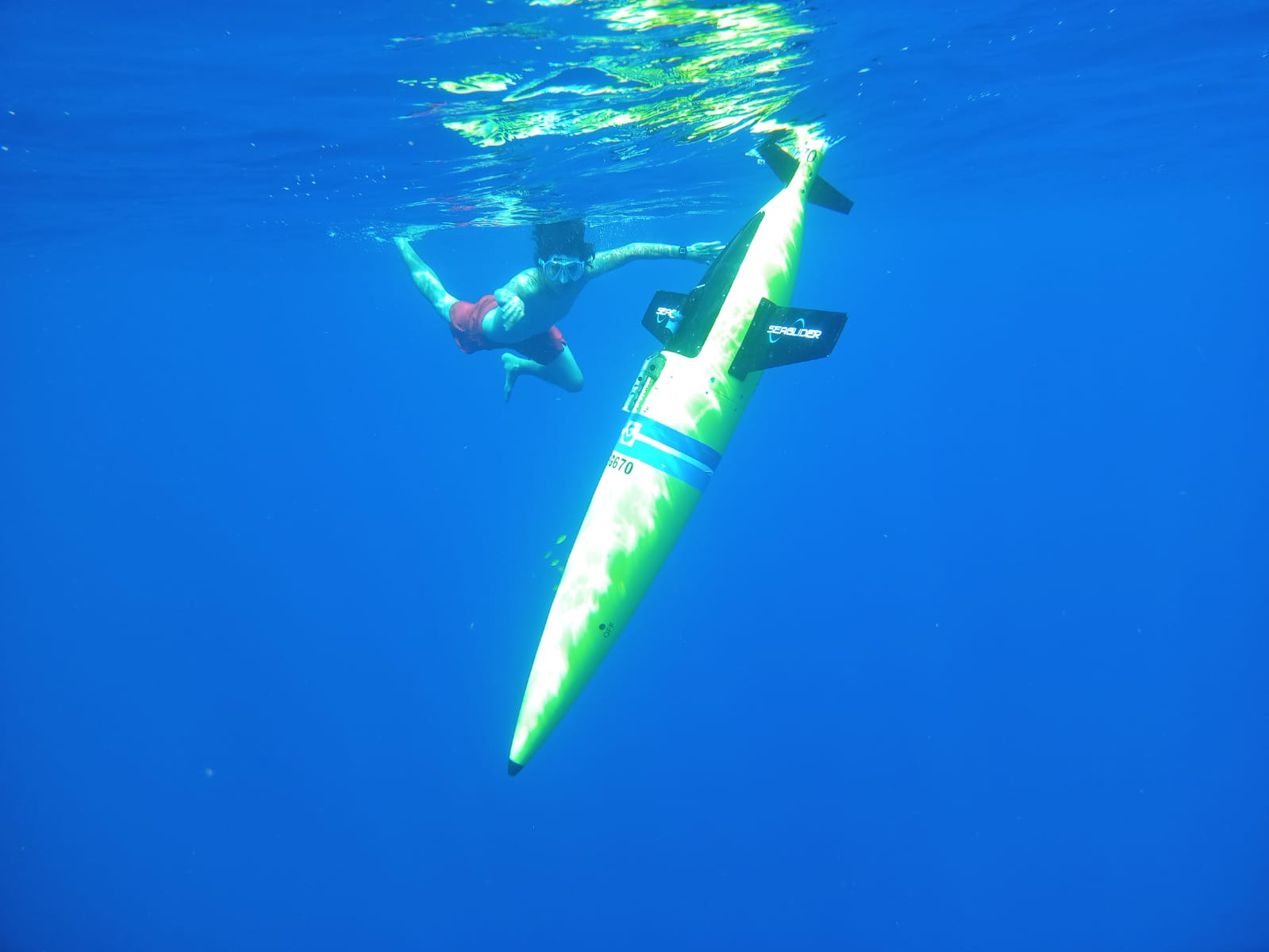 A large yellow hurricane glider underwater with a person next to it.