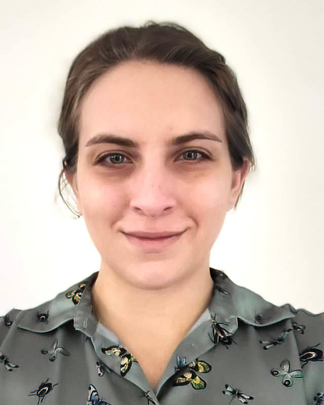 Headshot of Madison Soden, caucasion woman with dark hair, wearing a grey colalred shirt with butterflies in front of a white background