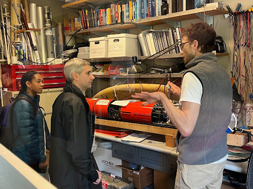 Three scientists in a laboratory where a red scientific instrument, called a glider, is laying on a table.