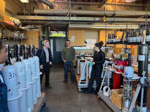 A laboratory filled with tall grey instruments with numbers labelling them and other various tools and metal parts.