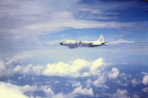 Photograph of a Lockheed P-3 airplane suspended in air, blue skies and scattered clouds in the background