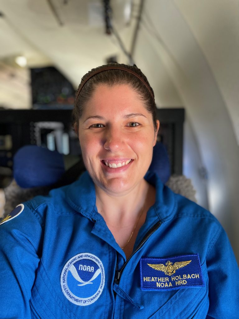 Fotografía retrato en color de Heather Holbach, subdirectora del programa Hurricane Field 2023, a bordo de un avión Lockheed WP-3 Hurricane Hunter.