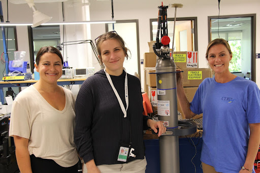 Three female scientists stand together in a laboratory.