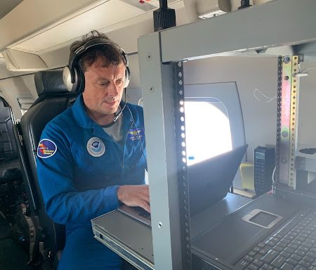 AOML meteorologist Jason Dunion sitting at his computer on the G-IV Hurricane Hunter aircraft.