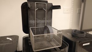 AMDL_3D_Printing_ALCOHOL-(1) Black container with a metal cage inside depicts where pieces are placed to begin the alcohol bath