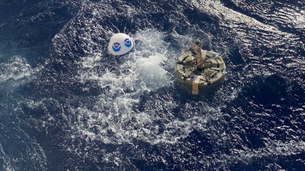 THE Surface drifter a metlal ring with cables lifted and tossed into the blue ocean creates whitewater as it splahes at the surface tied to a blue and white noaa BUOY WITH THE noaa LOGO, the instrument to be deployed to the deep sea of the Indian Ocean I08S GO-SHIP CRUISE