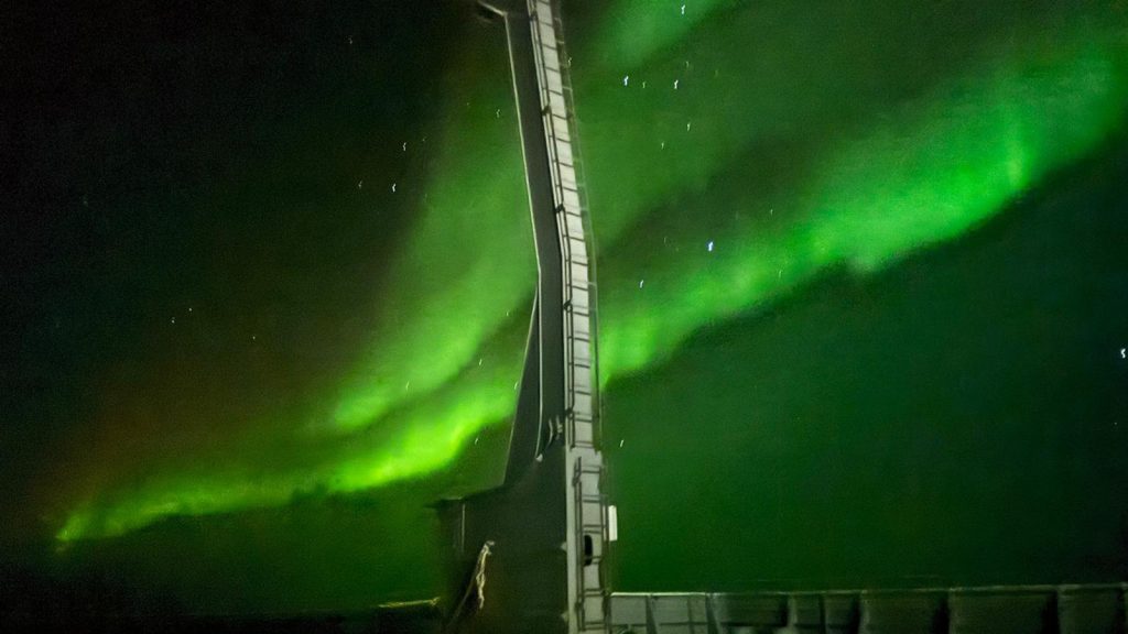 A STREAK of greenlights filled the night sky and covers the stars behind the white metal crane that lifts the CTD and the gunnel of the hsip in the bottom edge of the photo on the I08S GO-SHIP Cruise
