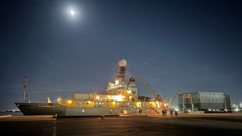 The R/V Thomas Thompson at the dock in Fremantle, Australia benath the night sky with the glimmer of the moonlight trickling from above and the yellow lights of the ship beaming like stars stolen from the darkness above