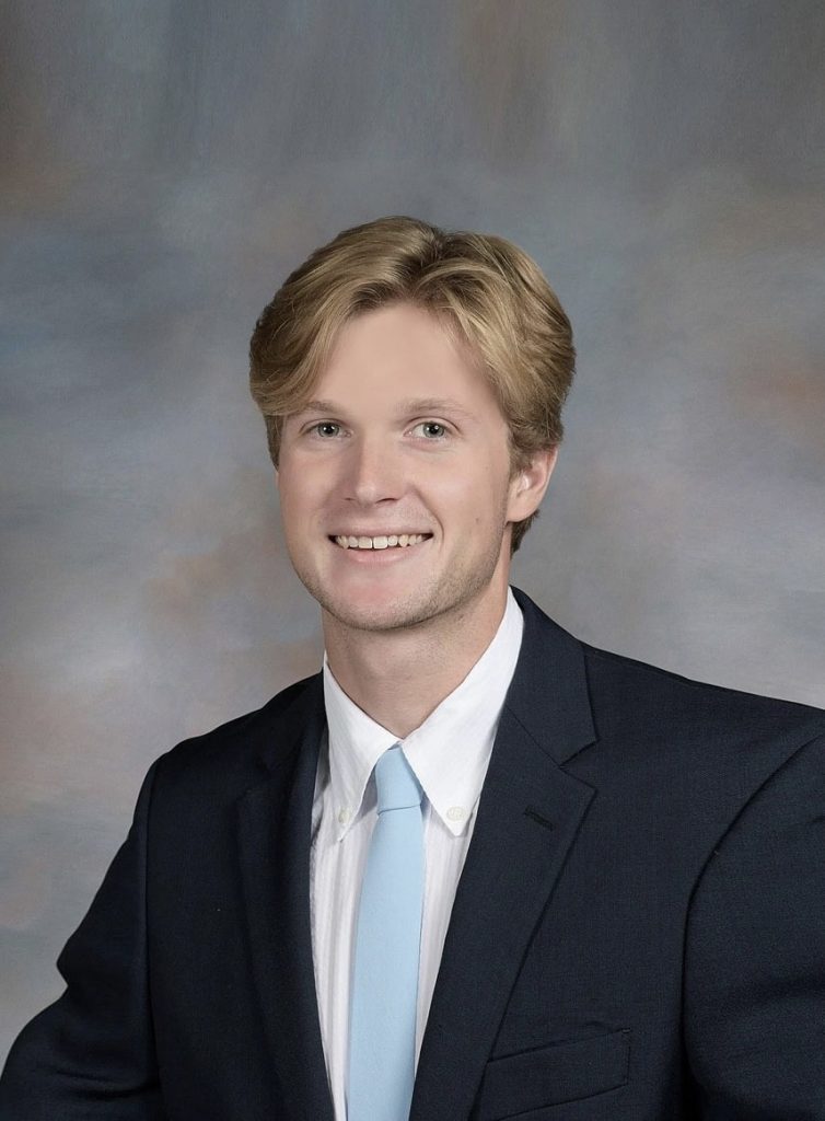 Evan_AOML_Bio_Headshot Evan Josza smiles as photo taken with suite, white button down blue tie